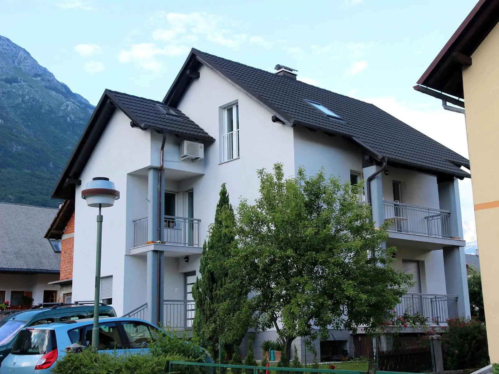 Hiša Brdo 48: bela hiša z balkoni in gorami v ozadju